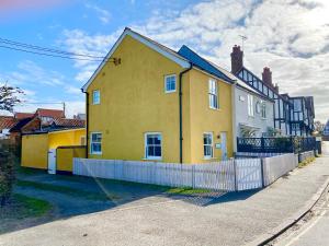 a yellow house on the side of a street at 1 South Cottages in Thorpeness