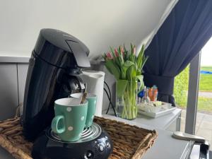 Hotelhuisjes Andijk في انديجك: وجود آلة صنع القهوة على طاولة مع كوب قهوة