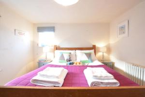 a bedroom with a purple bed with towels on it at 1 South Cottages in Thorpeness