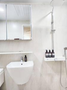 a white bathroom with a sink and a mirror at Home Woodsage in Seoul