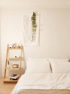 ソウルにあるHome Woodsageの白いベッド1台、壁に植物が備わるベッドルーム1室が備わります。