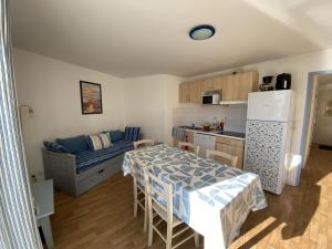 a small kitchen with a table and a refrigerator at Le Souvenir Intemporel - Appartement avec Piscine Parking in Les Sables-d'Olonne