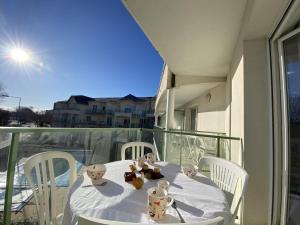d'une table blanche avec des chaises blanches sur un balcon. dans l'établissement Appartement avec piscine - La Chaume, à Les Sables-dʼOlonne