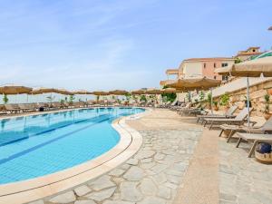 uma piscina com cadeiras e guarda-sóis num resort em Sanders Seaview Paphos em Klorakas