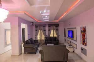 a living room with two chairs and a tv at VETTAS APARTMENT in Akure