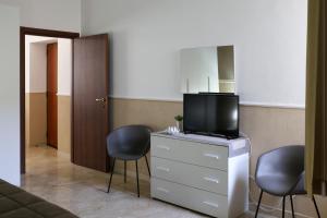 sala de estar con 2 sillas y tocador con TV en Dominique Comfort Apartment, en Reggio Calabria