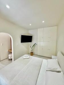 a white bedroom with a bed and a flat screen tv at Parakladi unique stay in Agios Nikolaos
