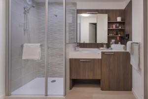 uma casa de banho com um chuveiro, um lavatório e um espelho. em Domitys l'Esquisse em Valenciennes