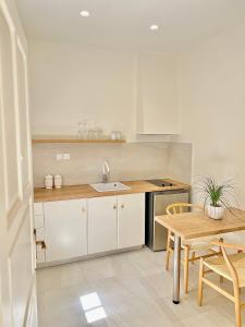 a kitchen with white cabinets and a table and a sink at Parakladi unique stay in Agios Nikolaos
