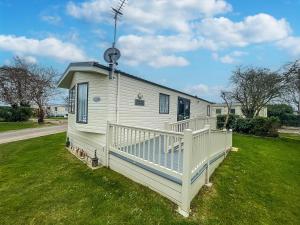 una casa blanca con un porche en el césped en Great 4 Berth Caravan With Wheelchair Access In Suffolk, Ref 68129bs en Lowestoft