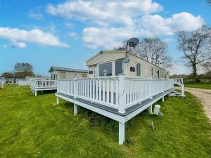 a white house with a porch on the grass at Lovely Caravan With Decking And Free Wifi In Lowestoft Ref 12106b in Lowestoft