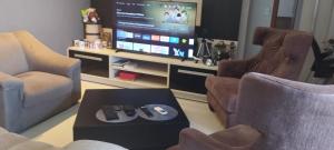 a living room with two chairs and a flat screen tv at Quarto Bem no Centro Dourados in Dourados