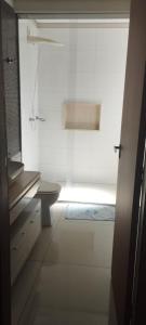 a white bathroom with a shower and a toilet at Quarto Bem no Centro Dourados in Dourados