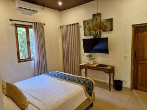 a bedroom with a bed and a table with a tv at Jepara Garden Resort in Jepara