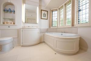 a bathroom with a tub and a toilet and a sink at Buckland Manor - A Relais & Chateaux Hotel in Broadway