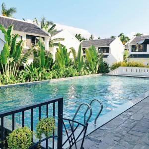 una piscina con due sedie di fronte a una casa di Én Garden Resort Hoian a Hiếu Nhơn