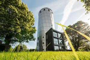 ein Gebäude in der Mitte eines Feldes mit Gras in der Unterkunft Wasserturm Pirach in Trostberg an der Alz