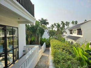 einen Balkon eines Hauses mit Bäumen und Pflanzen in der Unterkunft Én Garden Resort Hoian in Hiếu Nhơn