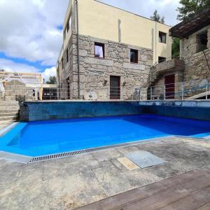 una gran piscina azul frente a un edificio en 7 bedrooms villa with private pool jacuzzi and furnished garden at Terras de Bouro, en Terras de Bouro