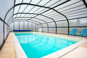 an indoor swimming pool with a large ceiling at Maison avec piscine 20min plage in Guerlesquin