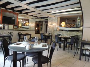 een restaurant met tafels en stoelen en een tv bij Logis Hôtel Restaurant L'Escale in Bellême