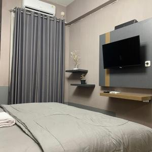 Apartemen Bale Hinggil Studio في Medokansemampir: غرفة نوم بسرير وتلفزيون بشاشة مسطحة