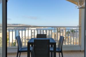 een tafel en stoelen op een balkon met uitzicht op de oceaan bij Designer home with stunning sea views in St Pauls by 360 Estates in St Paul's Bay