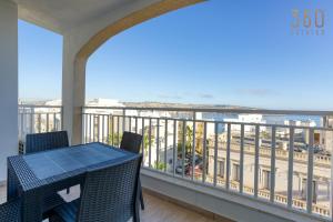 een balkon met een tafel en stoelen en de oceaan bij Designer home with stunning sea views in St Pauls by 360 Estates in St Paul's Bay