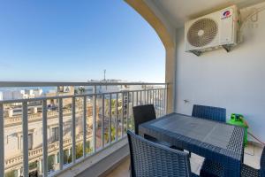 een balkon met een tafel en stoelen en uitzicht op de stad bij Designer home with stunning sea views in St Pauls by 360 Estates in St Paul's Bay