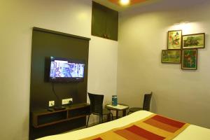 a hotel room with a bed and a tv at Shaleen Elegance Homestay Nakki Lake 400 meters in Mount Ābu