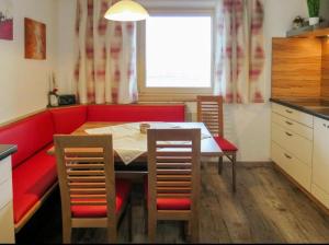 kuchnia z czerwoną kanapą, stołem i krzesłami w obiekcie Ferienwohnung Pendl w mieście Ramsau im Zillertal