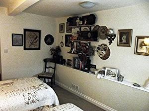 1 dormitorio con 1 cama y muchas fotos en la pared en The Apartment of Antiquity, en Kirkby Stephen