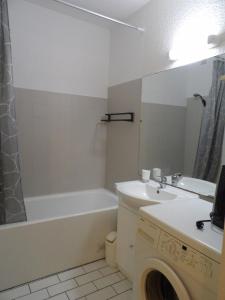 een badkamer met een wastafel, een bad en een wasmachine bij Appartement 4 personnes avec terrasse au golf de St Cyprien in Saint-Cyprien