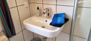 ein weißes Waschbecken im Bad mit einem blauen Handtuch in der Unterkunft Pension Regina/Gräfenhaus in Cochem