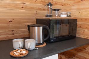 a kitchen counter with a microwave and two coffee mugs at Glamping Pod 3 Harmony in Scarborough