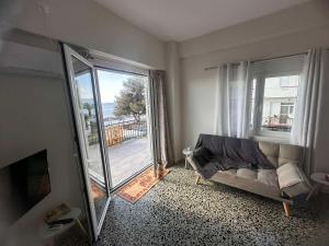 a living room with a couch and a large window at Agioi Theodoroi Beachview Chic Modern Apt in Agioi Theodoroi