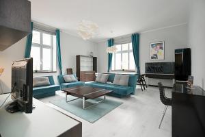 a living room with blue couches and a tv at Victus Apartamenty, Apartament Niebieski in Sopot