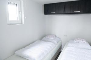 2 camas blancas en una habitación con ventana en Camping de Konijnenberg Tiny House, en Harderwijk