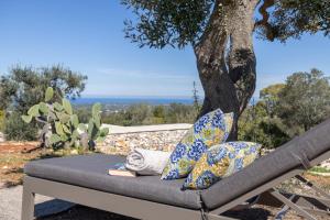 a bench under a tree with books and pillows at Trullo con vista mare e piscina riscaldata in Carovigno +15 photos