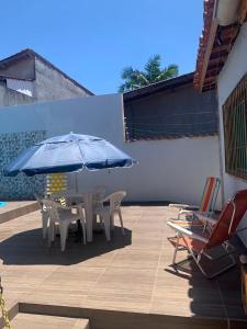 un patio con mesa, sillas y sombrilla azul en Kitnet Martin de Sa para casal, en Caraguatatuba