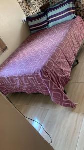 Una cama con un edredón morado y almohadas en el suelo. en Kitnet Martin de Sa para casal, en Caraguatatuba 9 fotos más