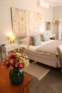 a bedroom with a bed and a vase of flowers on a table at Daisy Country Lodge in Springbok