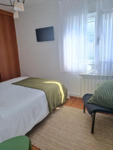 1 dormitorio con 1 cama, 1 silla y 1 ventana en La Campanilla-Suances, en Suances