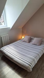 ein großes Bett mit zwei Kissen in einem Schlafzimmer in der Unterkunft Maison de la Grève in Ouistreham