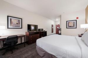 a hotel room with a bed and a desk with a computer at Cobblestone Hotel & Suites - Russells Point at Indian Lake in Russells Point