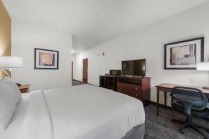 a hotel room with a bed and a desk and a chair at Cobblestone Hotel & Suites - Russells Point at Indian Lake in Russells Point