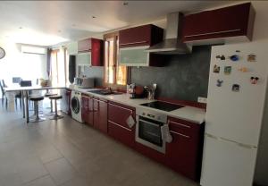 uma cozinha com armários vermelhos e um frigorífico branco em Le Chalet de Julia em Vignale