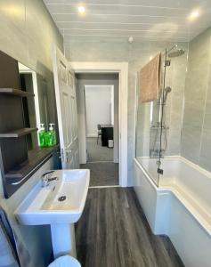 a bathroom with a sink and a tub and a shower at Bailey’s Townhouse in Belfast