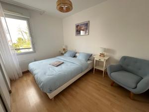 ein Schlafzimmer mit einem Bett und einem blauen Stuhl in der Unterkunft La garenne, près des commerces in Saint-Jean-de-Monts