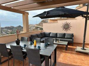 a patio with a table and a couch and an umbrella at Casa LA FLEUR beautiful apartment with communal p in El Labradorcico